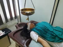 A patient receiving Shirodhara therapy at the clinic